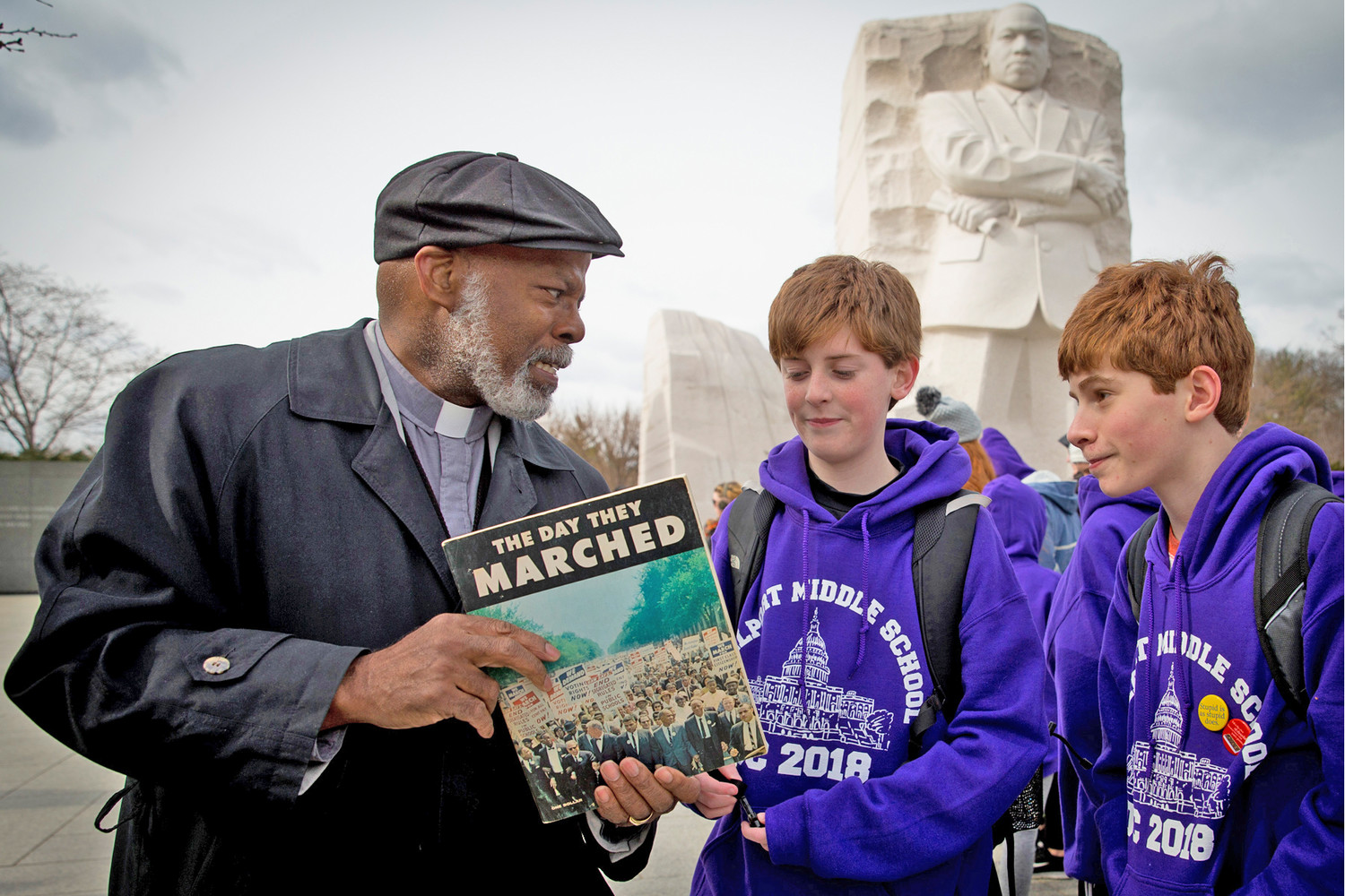 Deacon Timothy E. Tilghman of Our Lady of Perpetual Help Catholic Church in Washington shows two middle school students a program from the 1963 March on Washington for Jobs and Freedom, featuring the Rev. Martin Luther King Jr., while the deacon and youths visit the King memorial in Washington March 14. Deacon Tilghman was 15 when Rev. Dr. King was assassinated April 4, 1968. He accompanied his father as he traveled through Washington to help those who were impacted during the riots that ensued.